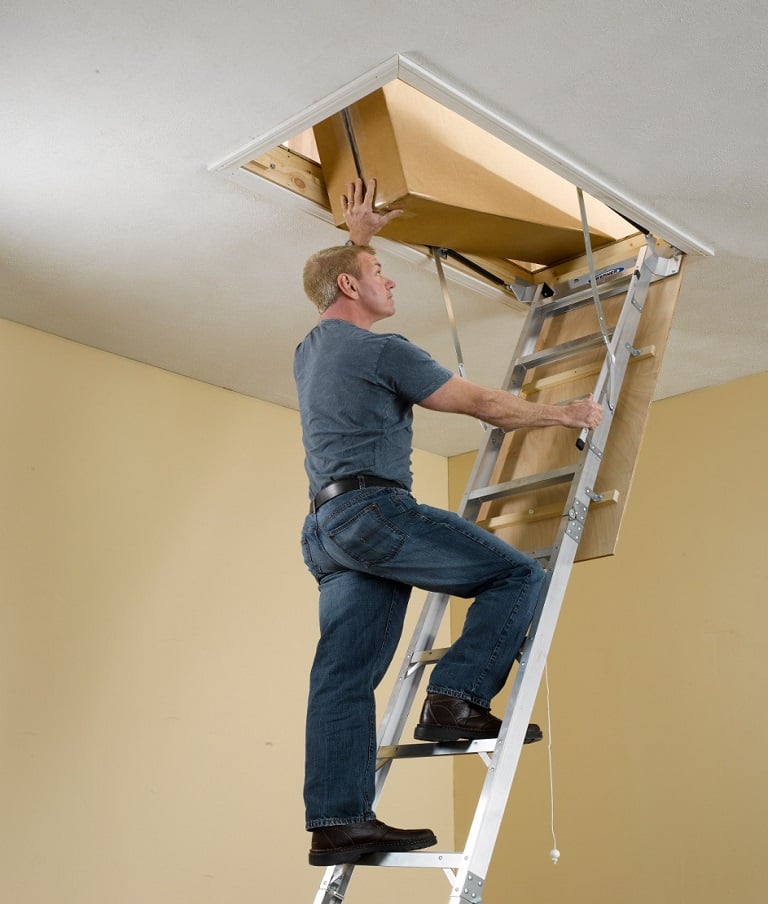 Man climbing a Werner AH2510 aluminum attic ladder